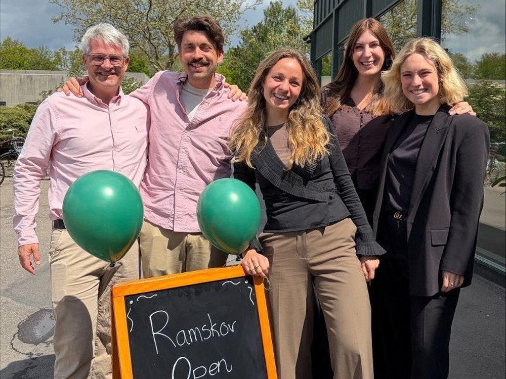 Ramskov colleagues by a Ramskov Open welcome sign with green balloons